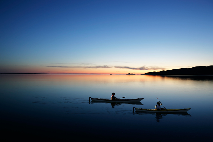 father and son kayaking on serene lake at twilight